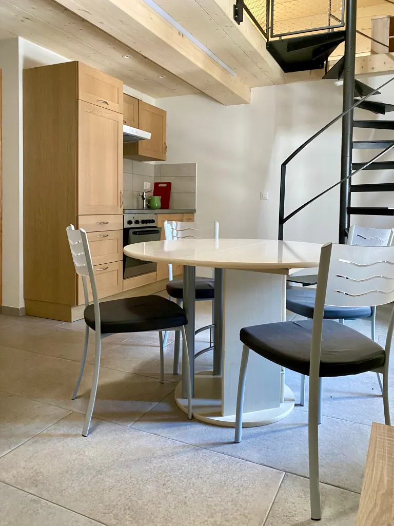 Table à manger, cuisine et escalier en colimaçon